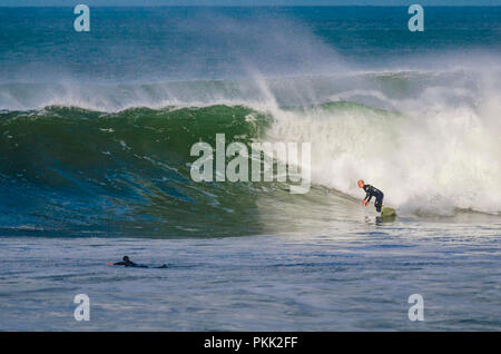 Surfer effettuando un giro di fondo su una grande onda A Bells Beach, Great Ocean Road, Victoria, Australia Foto Stock