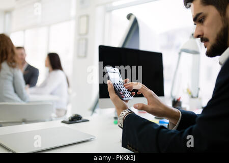 Immagine di uomo occupato utilizzando la calcolatrice in office Foto Stock