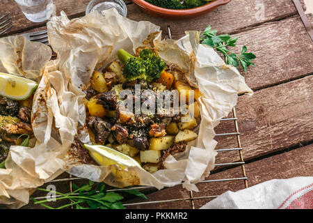 Tradizionale greco kleftiko, un forno a legna stufato di agnello con patate, olio di oliva, cipolla, carota, aglio ed erbe aromatiche, servito con limone e ouzo. Foto Stock