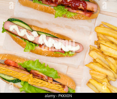 Scelta di tre diverse hot dogs con assortimento di insalate fresche passamaneria e rabboccato con mostarda, mayo o senape visto dal di sopra con patate fritte Foto Stock