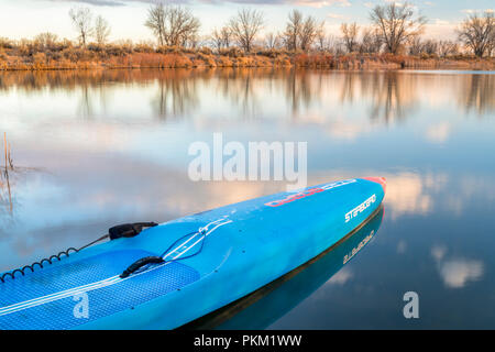 Fort Collins, CO, Stati Uniti d'America - 17 Marzo 2018: Racing stand up paddleboard su di un lago calmo al tramonto - 2018 modello di tutte le stelle sup da dritta. Foto Stock