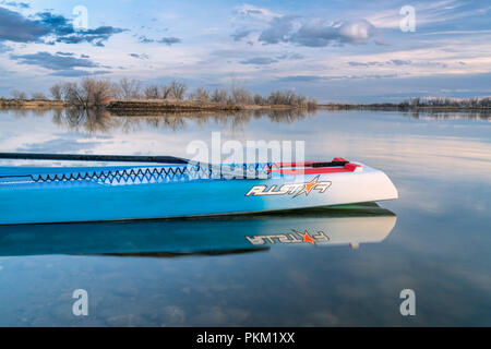 Fort Collins, CO, Stati Uniti d'America - 21 Marzo 2018: Racing stand up paddleboard su di un lago calmo al tramonto - 2018 modello di tutte le stelle sup da dritta. Foto Stock