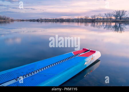 Fort Collins, CO, Stati Uniti d'America - 21 Marzo 2018: Racing stand up paddleboard su di un lago calmo al tramonto - 2018 modello di tutte le stelle sup da dritta. Foto Stock