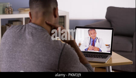 Nero a parlare del paziente al medico che utilizza un notebook Foto Stock