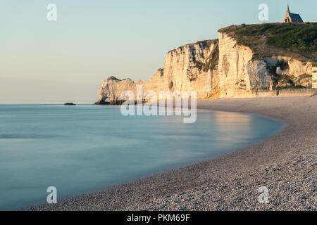 Spiaggia di Etretat con la cappella di Notre Dame de la Garde sulla sommità delle scogliere di gesso su una soleggiata sera in estate (Normandia Francia) Foto Stock