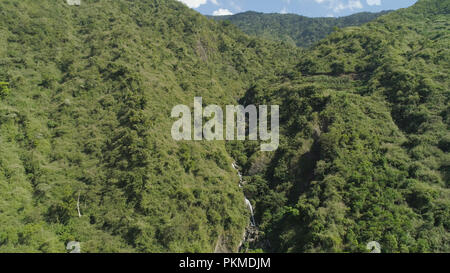Vista aerea della cascata nelle montagne della Cordigliera filippina. Cascata in montagna. una cascata che scorre sulle pendici delle montagne coperte di vegetazione tropicale. Filippine, Luzon Foto Stock
