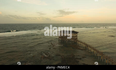 Punto di vista nell'oceano al Cloud Nine punto surf al tramonto, Siargao island , Filippine. Vista aerea sollevata passerella in legno per surfisti di attraversare la barriera corallina di siargao island al cloud 9 surf break sull isola di Mindanao. Isole Siargao famoso surf break cloud 9. Volare sopra il mare blu nelle acque azzurre della laguna. Foto Stock