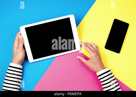 Donna con le mani computer tablet e smartphone su sfondo colorato. Foto Stock