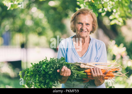 Senior donna tenendo raccolto fresco dal suo giardino Foto Stock