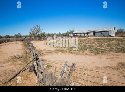 Vecchio tosatura delle pecore capannone, recinzioni e arida terra sotto il cielo blu in outback Australia durante la siccità Foto Stock