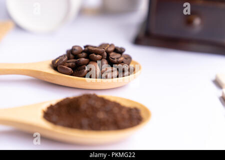 Cucchiai di legno riempita con terreno frantumato del caffè su sfondo bianco, close up Foto Stock