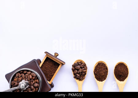 Cucchiai di legno riempito di caffè in grani frantumati e caffè macinato , macinacaffè in legno su sfondo bianco, vista dall'alto Foto Stock