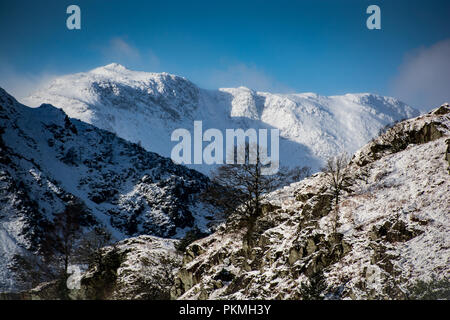 Vista invernale di Wetherlam da The Langdale Valley, Lake District inglese con piena copertura di neve, cielo blu e spindrift dal vertice Foto Stock