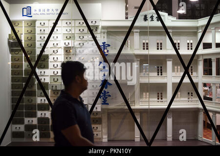 Kowloon, Hong Kong. Xiv Sep, 2018. Un pedone vede passando da Hong Kong Battista Scuola universitaria di medicina cinese Lui Seng Chun con nastrato per porte e finestre.porte e finestre di edifici sono stati fissati con nastro adesivo davanti a Super Typhoon Mangkhut arrivo a Hong Kong, Cina. È atteso a terra con un tifone segnale n. 8. Credito: Miguel Candela/SOPA Immagini/ZUMA filo/Alamy Live News Foto Stock