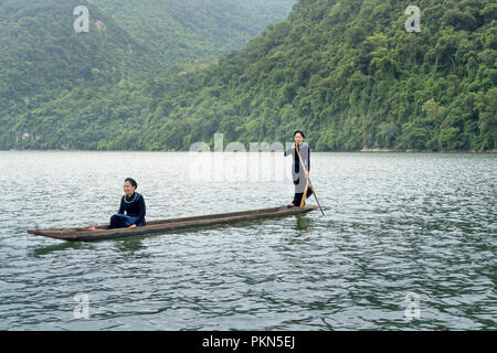 Una donna della minoranza etnica Tay nel suo costume tradizionale è il canottaggio una piroga su Ba essere Lago. Foto Stock