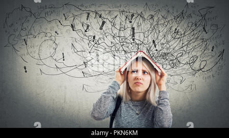 Confuso donna giovane studente tenendo un libro aperto sopra la testa. Ha sottolineato l'emozione, infelice sensazione, compito difficile da risolvere. Centinaia di frecce e la curva Foto Stock