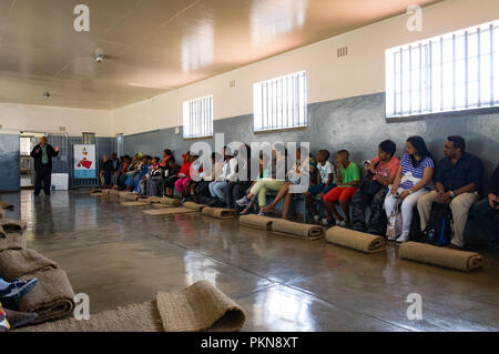 Un tour guida spiega la storia in un blocco comunale di Robben Island (Robbeneiland), il Sud Africa, la prigione di Nelson Mandela Foto Stock