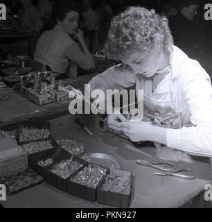 Degli anni Cinquanta, storico, un lavoratore di sesso femminile che seduti su un banco di lavoro dal cablaggio lato componenti elettrici per un wireles tubo vuoto radio sul piano della fabbrica della British produttore elettrico Radio Bush, Londra, Inghilterra. Molti esperti la fabbrica di posti di lavoro precedentemente svolto dagli uomini sono stati presi in consegna durante il WW2 da donne e hanno continuato in questi ruoli nel dopoguerra. Foto Stock