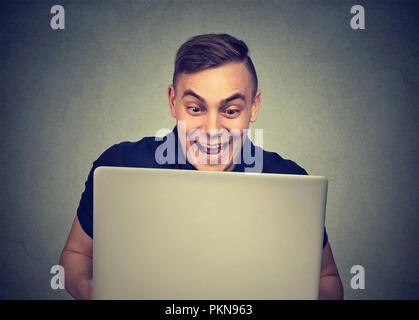 Moderno e giovane in grande sorpresa la navigazione portatile su sfondo grigio Foto Stock