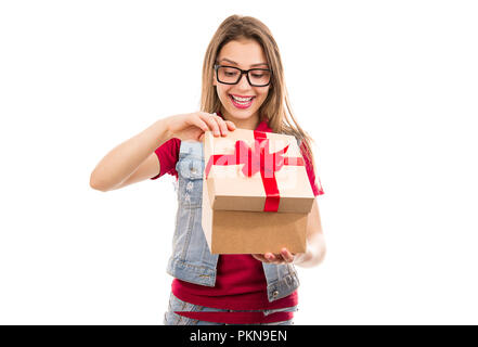Affascinante giovane donna guardando all interno della confezione regalo con fiocco rosso isolato su sfondo bianco Foto Stock