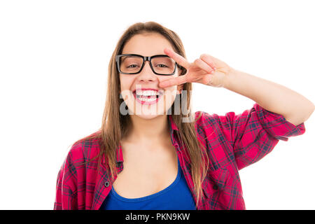 Giovane affascinante ragazza adolescente in plaid shirt tenendo la mano vicino al viso con v-segno sorridente in telecamera isolata su sfondo bianco Foto Stock