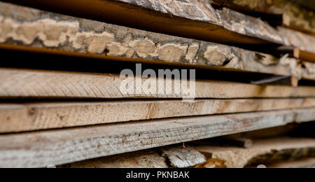 Ripiegate legno marrone e grigio di tavole in una segheria. Impilate le schede ontano come texture. Foto Stock