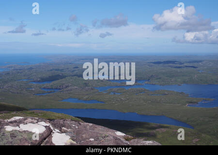 Una vista da stac Pollaidh guardando a nord ovest verso la penisola di Stoer attraverso molti piccoli laghi all'orizzonte su una luminosa giornata di sole Foto Stock