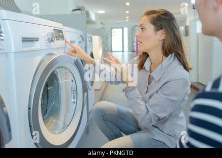 Coppia in cerca di macchina di lavaggio in negozio Foto Stock