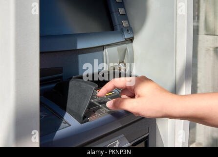 ATM con la tastiera e il canto della giovane donna toccando il codice pin Foto Stock