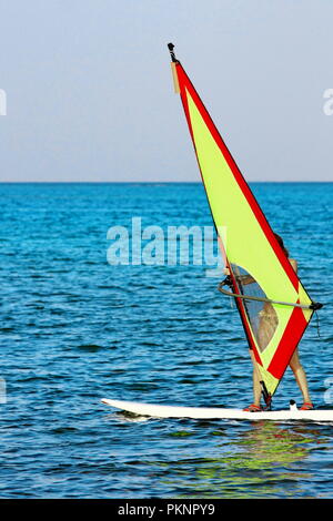 Windsurf, mare blu e giallo vela. Il surfer che esercitano in mare calmo o oceano Foto Stock