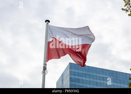 Bandiera della Polonia. Bandiera polacca su un palo sventolare, moderno edificio sullo sfondo Foto Stock