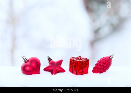 Vacanze di Natale Decorazioni rosso, cuore, pigna e dono nella neve su blured sfondo bianco Foto Stock