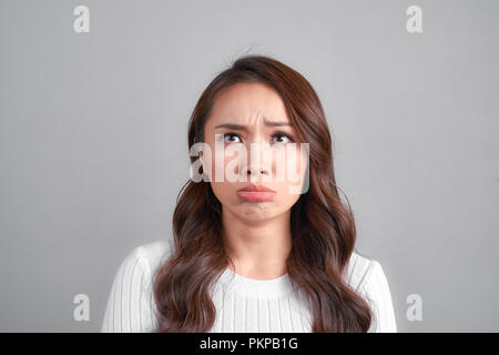 Giovane bella donna tristi e gravi in questione cercando preoccupata e riflessivo espressione facciale depressa isolato sfondo grigio nella tristezza Foto Stock