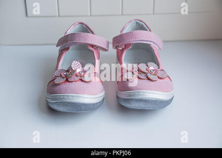 Coppia di simpatici baby sandali decorati con fiori su fondo bianco, copia dello spazio. Le ragazze fashion.baby pink scarpe di cuoio isolato su bianco.bambina abiti collezione. Foto Stock