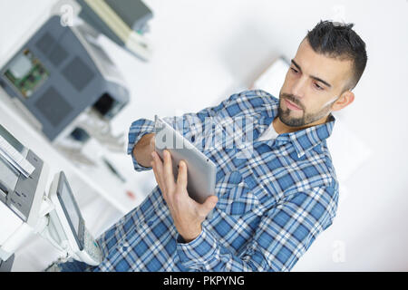 Uomo di dare il comando di stampa sulla tavoletta digitale in ufficio Foto Stock