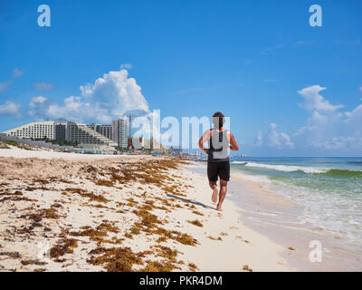 Giovane uomo jogging sulla spiaggia tropicale paradiso di Playa Delfines, Cancun, Messico, 7 settembre 2018 Foto Stock