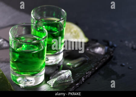 Due bicchieri di assenzio con calce e ghiaccio su uno sfondo scuro Foto Stock