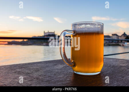 Vetro freddo boccale di birra con schiuma sullo sfondo il castello di Bratislava, Slovacchia Foto Stock