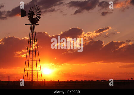 Bella silhouette fuori da un mulino a vento durante un bel tramonto su una vasta piana aperta. Foto Stock