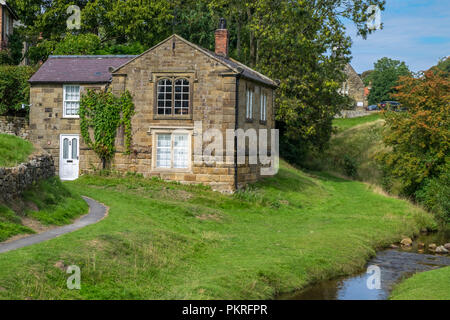 Caratteristico il cioccolato-box cottage da un flusso in Hutton Le Hole, North Yorkshire Foto Stock