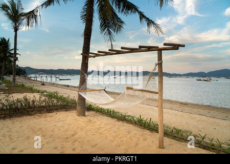 Beachside amaca legata ad un albero con una vacanza rilassante sulla sabbia bianca spiaggia tropicale e cielo blu si trova il Phu Yen provincia. Il Vietnam Foto Stock