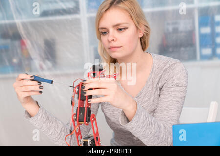 Giovane femmina attraente ingegnere di lavoro sul progetto di robotica Foto Stock