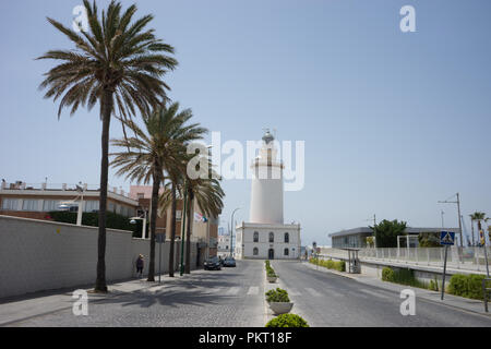 Spagna, Malaga - 24 Giugno 2017: alte palme davanti un faro bianco a Malagueta spiaggia di Malaga, Spagna, Europa su un luminoso giorno di estate Foto Stock