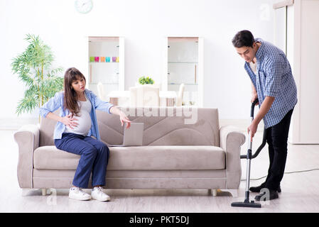 L'uomo aiutando moglie incinta nella pulizia Foto Stock