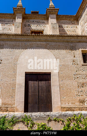 Moresco arco islamico al di sopra di una porta di legno in Granada, Spagna, Europa in una luminosa giornata di sole Foto Stock