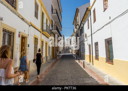 Spagna, Ronda - 21 giugno 2017: vista posteriore della gente che cammina sulla strada tra gli edifici Foto Stock