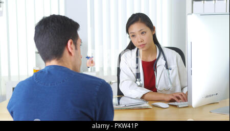 Asian medico rivedendo xray con paziente Foto Stock