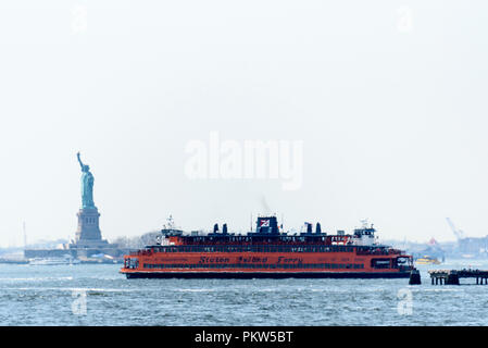 04-2018 New York, Stati Uniti d'America. Fotografato attraverso un calore haze, Staten Island Ferry passa la Statua della Libertà. Foto: © Simon Grosset Foto Stock