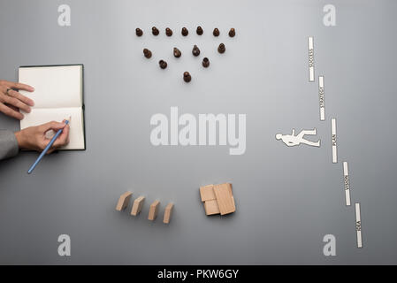Vista superiore della imprenditrice creando la sua visione aziendale sulla scrittura di appunti con blocchi di legno, i pezzi e le parole di realizzazione sul banco grigio. Foto Stock