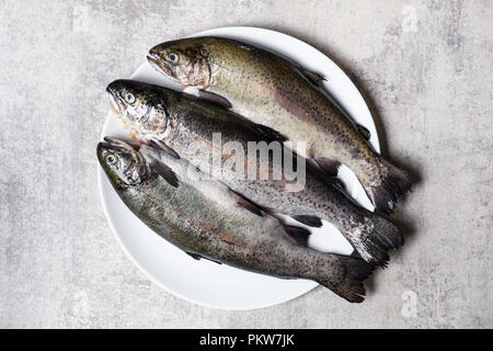 Tre trote pesce sulla piastra bianca Foto Stock